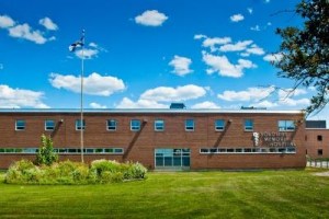 一幢两层红砖建筑，草坪上有一根旗杆。