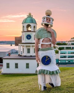 一个穿着时钟服装的人站在镇钟旁边