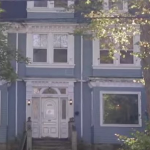 A blue three-storye house with white trim