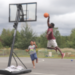 Two Black youths playing basketball outdoors
