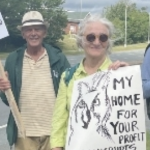 两名中年抗议者举着标语靠近一条铺好的道路