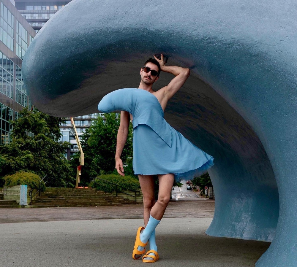 在哈利法克斯海滨，一名穿着波浪服装的男子站在波浪雕塑前。