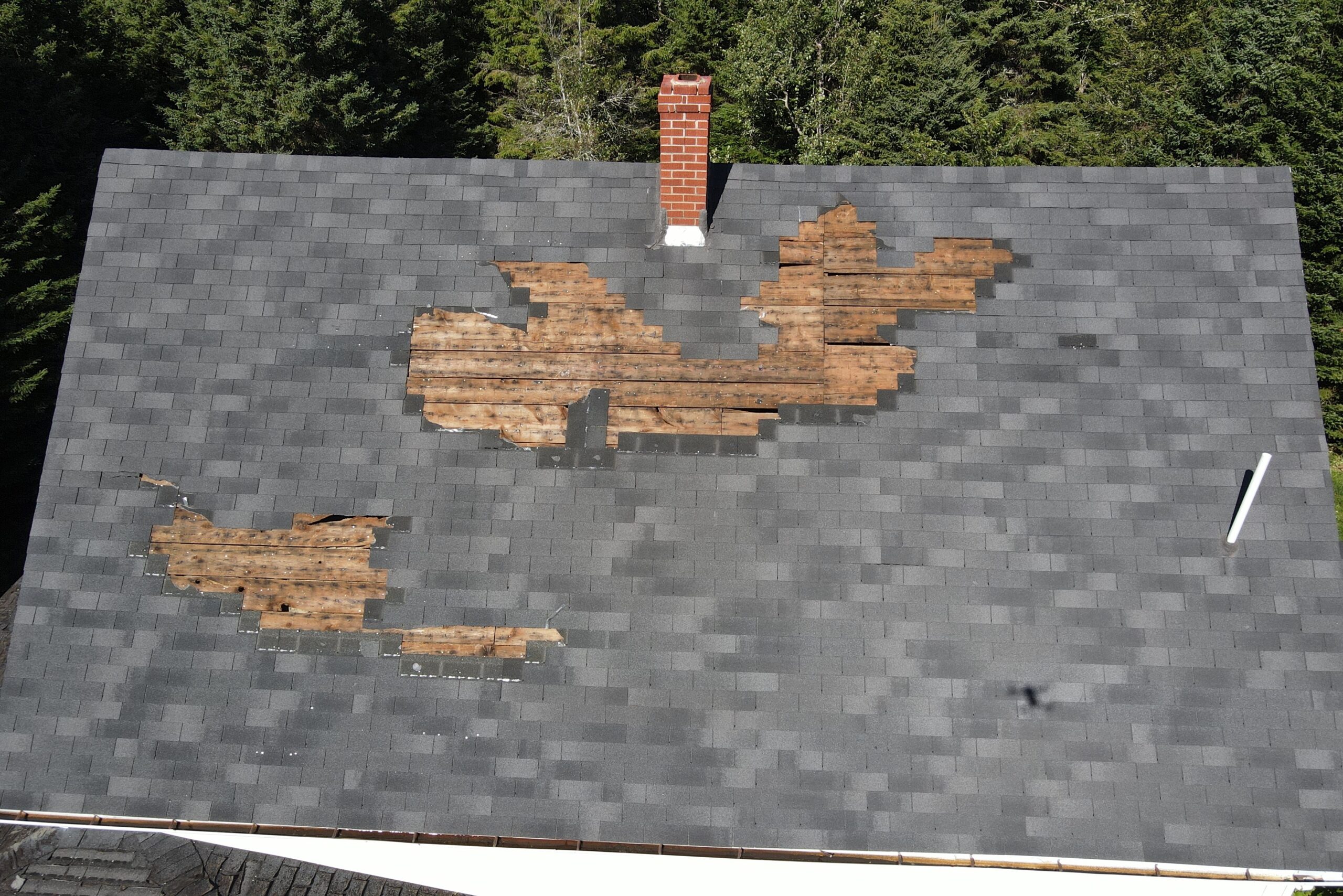 灰色瓦片的屋顶，有些瓦片已经被撕破了。屋顶中间有一个烟囱