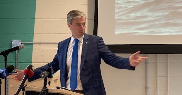 一个穿着蓝色西装外套、白衬衫、蓝色领带的男人，双手分开