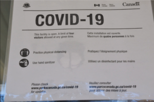 浴室门上的标牌上写着“Covid - 19，任何时间最多允许四人到访，保持身体距离，使用洗手液”