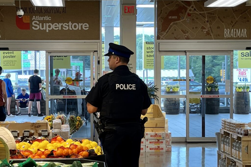 一名穿制服的警察站在杂货店门口的桔子和柠檬旁边。