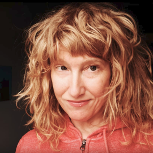 一个女人穿着一件橙色的拉链连帽衫，带着红色波浪披肩及肩。