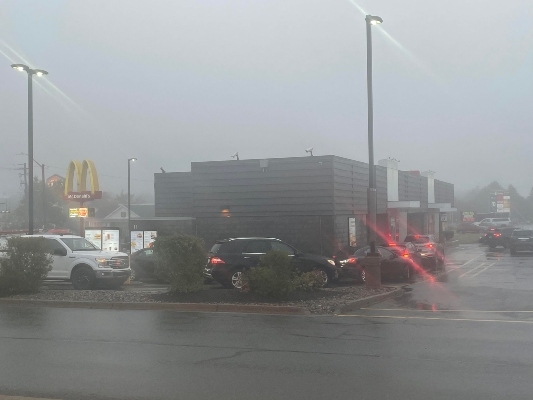 在一个多云的早晨，快餐店里的一排汽车驶过