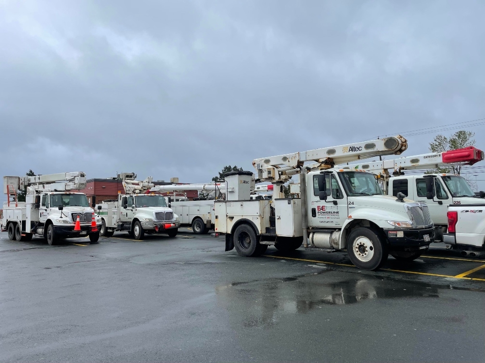 在阴云密布的天空下，大型白色多用途卡车在停车场等待。