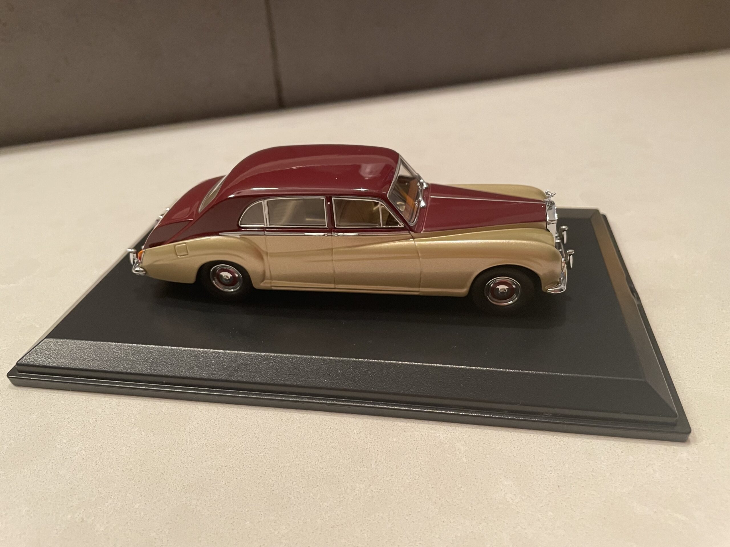 桌上放着一辆酒红色和米色相间的玩具车