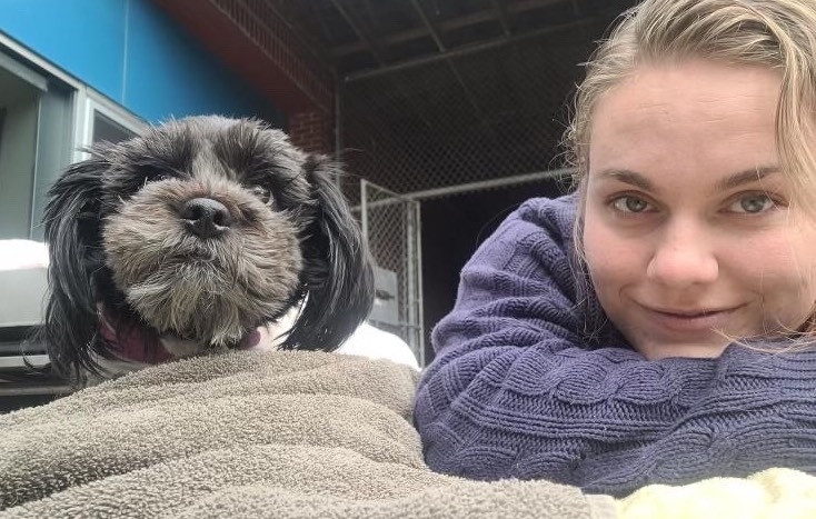 一个女人和她的狗躺在床上，面对着镜头