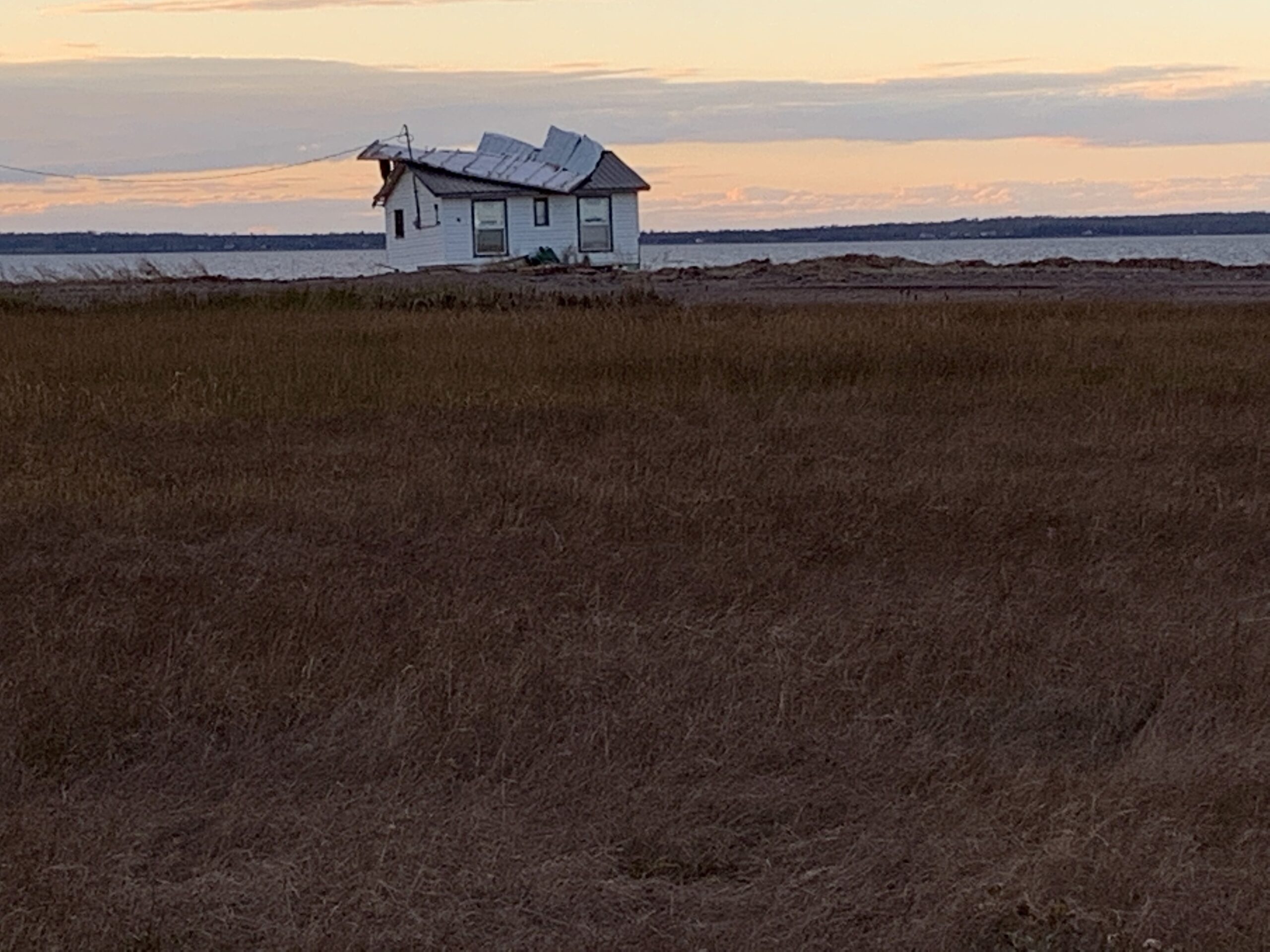 沿着海岸线的一座白色小屋的屋顶上有另一个屋顶
