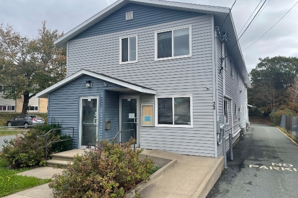 一栋灰色的两层楼房，前面有一个轮椅坡道。几棵灌木装饰着前院