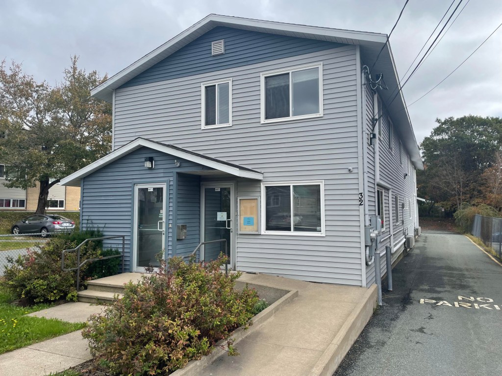 一栋灰色的两层楼房，前面有一个轮椅坡道。几棵灌木装饰着前院