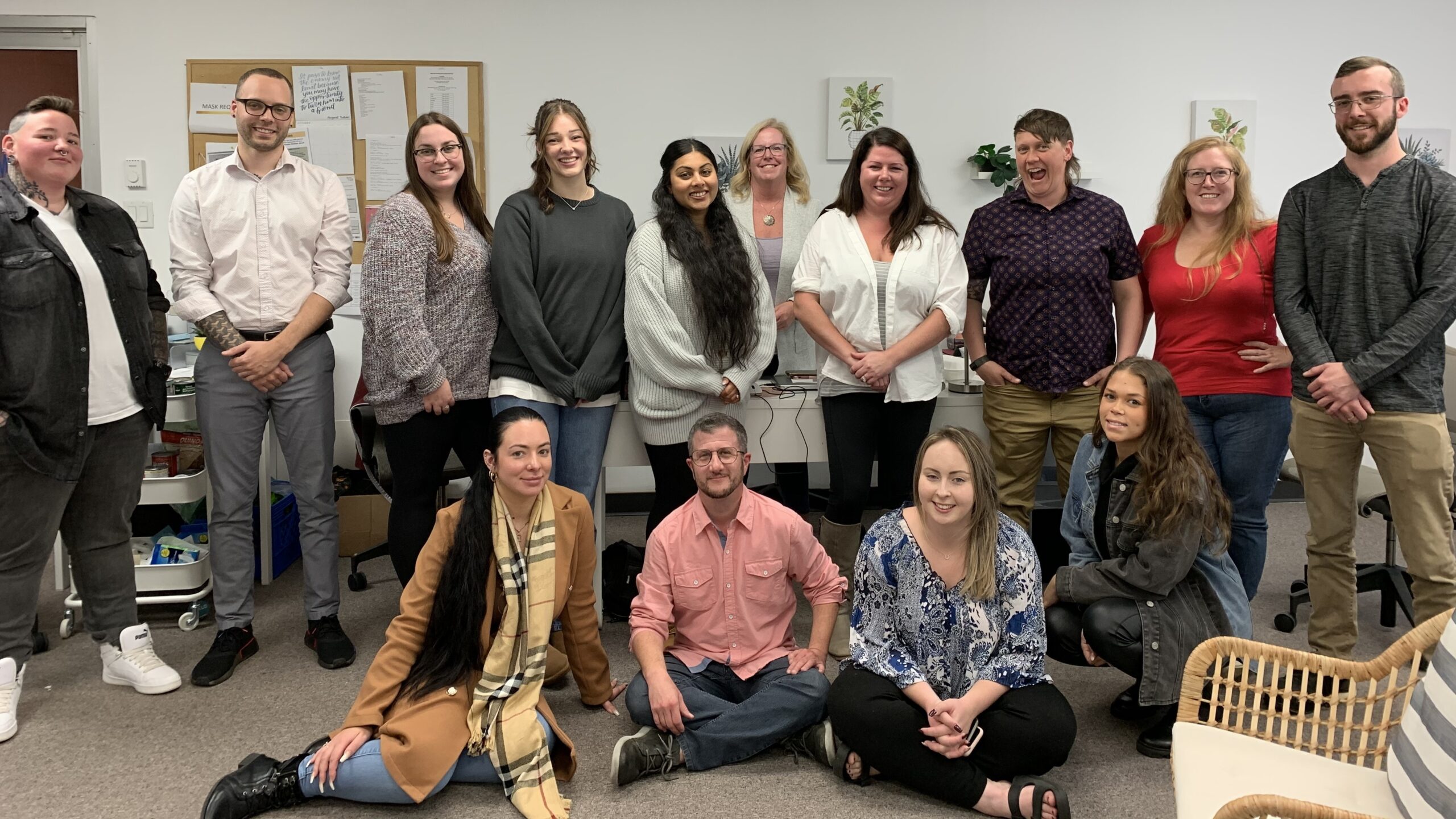 一群人在办公场所摆姿势拍照。有四个人坐在前排，其余的人坐在后排。